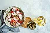 Vegetable salad with organic tomatoes, radishes, and capers, served with lemonade
