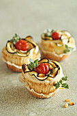 Puff pastry tarts with zucchini, cherry tomatoes, cream cheese and pine nuts