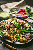 Grilled chicken thighs with red onions and basil leaves, served with green sauce