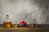 Small carafe and glass with rum, bowl with raspberries and chocolate block