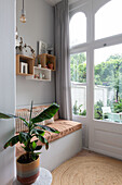 Cosy reading corner with bench next to large window with garden view