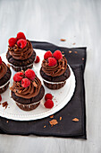 Chocolate cupcakes with chocolate topping and raspberries