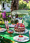 Garden table with chocolate cake and summer flowers in a vase