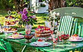 Gedeckter Gartentisch mit Kuchen und frischen Beeren im Sommer