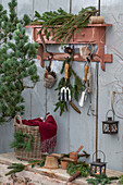 Weihnachtsdeko auf der Terrasse mit Tannenzweigen und Zapfen an rustikaler Garderobe hängend
