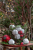 Christbaumkugeln und Schneebälle aus Webpelz in Drahtkorb, Nadelzweige auf Teller, Weihnachtsdekoration