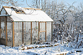 Gewächshaus und Beete im verschneiten Garten im Winter