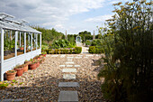 Vegetable garden with greenhouse, pots, gravel, and stone pathway