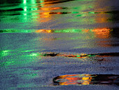 Lights reflected in puddles on asphalt path