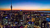 Auckland, Neuseeland. Der Auckland Skytower und der Hafen bei Nacht.