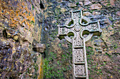 Ein kunstvolles keltisches Kreuz markiert ein Grab in einer historischen irischen Kirche, Grafschaft Mayo, Irland.
