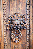 Italy, Umbria, Assisi. Ornate wood carved door knocker.
