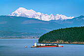 Öltanker in der Fidalgo Bay, der zur March Point Raffinerie geschleppt wird, Anacortes, Washington State. Der Mount Baker ist in der Ferne zu sehen.