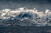 Südgeorgien Insel. Eine Öffnung in den Wolken und Virga enthüllen die bergige und vergletscherte Landschaft.