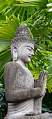 Indonesien, Bali. Buddha-Statue mit grünen Palmen.