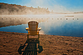 Canada, Ontario, Silent Lake Provincial Park. Muskoka chair and morning fog on Silent Lake.