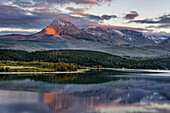 Divide Mountain catches alpenglow light at sunset over St. Mary Lake in Glacier National Park, Montana, USA