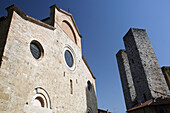 Church and two of the Towers of San Gimignano, a famous medieval hilltop town with old towers, in Tuscany. Italy. June.
