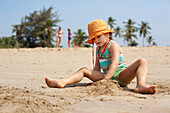 Kiki Lett baut Sandburgen im Urlaub in Indien, Turtle Beach, Goa, Indien.