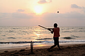 Kricketspiel, der Nationalsport Indiens, am Anjuna Beach bei Sonnenuntergang, Bundesstaat Goa, Indien, Asien.