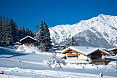 Snow Covered Alpine Scenery, With Mountains, Pine Trees, And Picturesque Ski Chalets At Ski And Snowboard Resort In Waidring, Austrian Alps, Austria