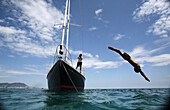 Ein Mann taucht von einer vor Gibraltar verankerten Yacht ins Meer.