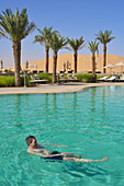 United Arab Emirates, Abu Dahbi, Qasr al Sarab, Tourist swimming in pool and dunes