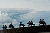 Kroatien, Silhouetten von Paaren, die auf Bänken an der Ufermauer sitzen; Dubrovnik