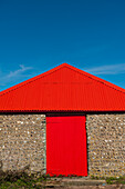 England, East Sussex, Bright red barn door and roof; Seven Sisters National Park