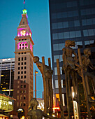 USA, Colorado, Bronze sculpture of children playing on stilts situated on 16th Street mall at night; Denver