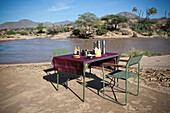 Kenya, Riverside breakfast table set up for guests at Joy's Camp; Shaba National Reserve