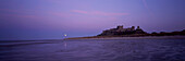 Großbritannien, England, Northumberland, Northumbrian Coast, Panoramablick auf den Mondaufgang über Bamburgh Castle und Strand; Bamburgh