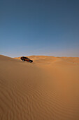 VAE, Abu Dhabi, Geländewagen fährt über Sanddünen; Liwa
