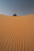 UAE, Abu Dhabi, Four wheel drive going across sand dunes; Liwa