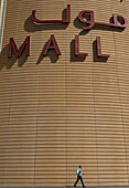UAE, Man walking past large sign for the Dubai Mall; Dubai