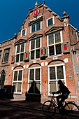 Silhouette eines Radfahrers, der an einem traditionellen holländischen Haus vorbeifährt,Amsterdam, Holland.