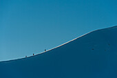 Walkers climbing snowy ridge of Sgorr Dhearg in winter near Glen Coe (Glencoe), Highlands, Scotland, UK.