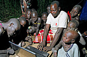 Gruppe von Mursi Stammeskindern, die in der tiefen Nacht den ersten Mursi eigenen Laptop-Computer in Betrieb nehmen. Makki / Süd-Omo / Region der südlichen Nationen, Nationalitäten und Völker (Äthiopien).