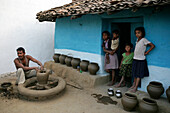 A Family Stands Outside Their Blue House With Pots On Display Outside, Potters Village; Madhya Pradesh, India