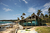 Ein blaues Gebäude am Wasser mit Palmen; Bequia Island, St. Vincent und die Grenadinen