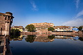 Mehrangarh Fort reflected in a city tank in Jodhpur Old Town; Jodhpur, Rajasthan, India