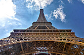 Low angle view of the Eiffel Tower against a cloudy blue sky; Paris, Ile de France, France
