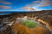 Volcanic rock formations and sunlight reflecting in the green tidal pool on the beach at Pointe des Chateaux; Grande-Terre, Guadeloupe, French West Indies