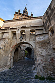 Torbogen und Kopfsteinpflasterstraße unterhalb des Uhrturms zur Zitadelle und Altstadt von Sighisoara, Geburtsort von Vlad Tepes (Dracula); Sighisoara, Siebenbürgen, Rumänien