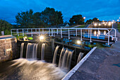 In der Abenddämmerung beleuchten Lichter die Schleusen des Caledonian Canal in Inverness, Schottland; Inverness, Schottland