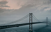 The 25 de Abril Bridge crossing the Tagus River, connecting Lisbon and Almada on a grey, foggy day; Lisbon, Estremadura, Portugal
