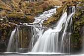 Wasserfälle, die über die Klippen in der zerklüfteten Landschaft stürzen; Island