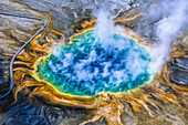 Grand Prismatic Spring ist eines der größten und schönsten Beispiele für eine häufige hydrothermale Erscheinung im Yellowstone-Nationalpark und eine der größten heißen Quellen in den Vereinigten Staaten. Das tiefe Blau in der Mitte ist das klare, überhitzte Wasser, das aus der unterirdischen Wärmequelle nach oben fließt, und wenn das Wasser an den Rändern des Beckens und auf den Sinterterrassen abkühlt, erzeugen Bakterien und Algen den Regenbogen der Farben. Diese heiße Quelle wurde in Osborne Russells "Journal of a Trapper" unter dem Namen "Boiling Lake" ausdrücklich erwähnt, ein Name, den ih