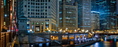View of the Chicago River crossing the DuSable Bridge and cityscape of iconic office towers, the London Guarantee Building and 35 East Whacker Building in the City of Chicago at night; Chicago, Cook County, Illinois, United States of America