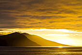 Clouds at sunrise above distant islands.